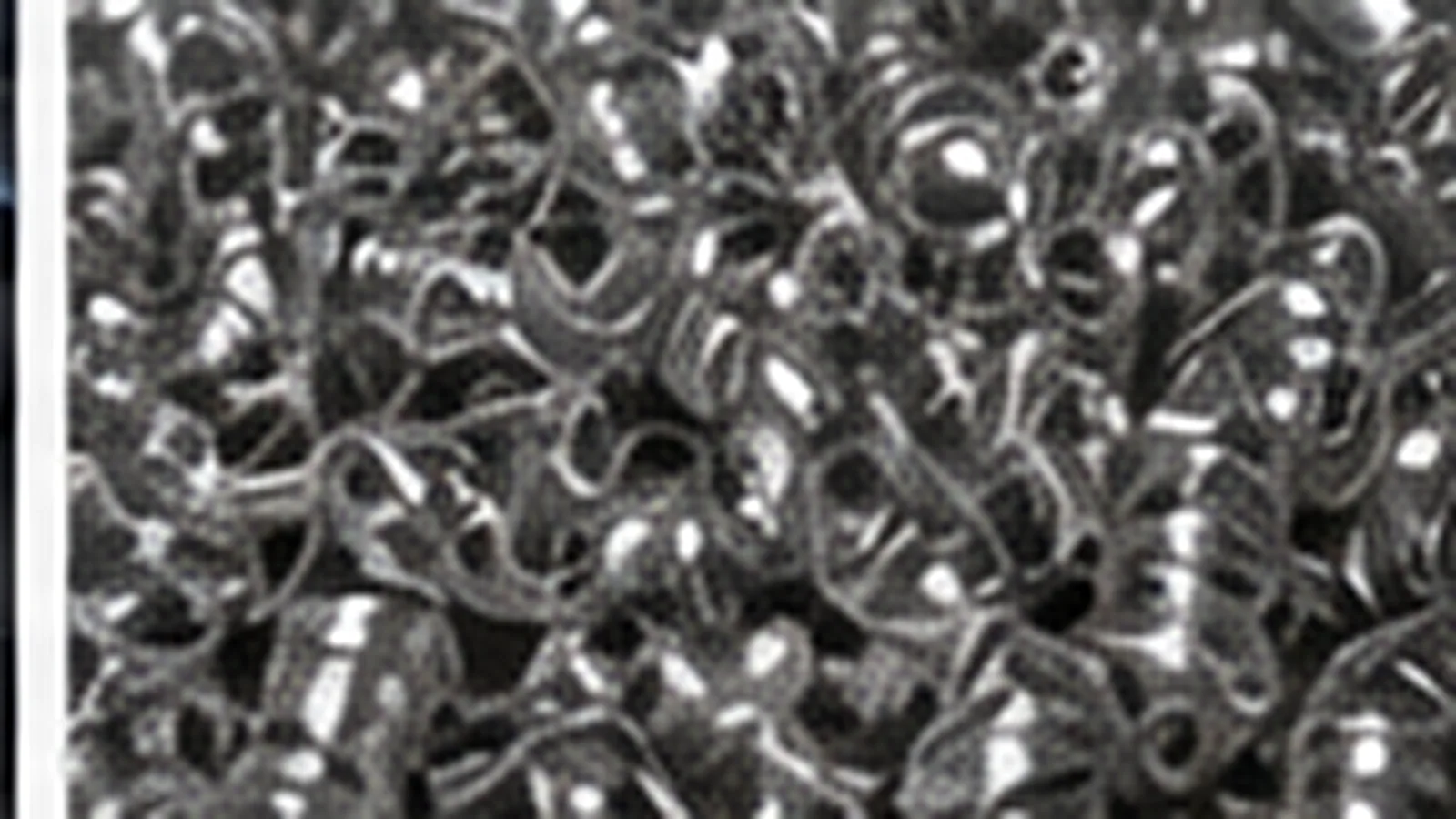Copeaux d'aluminium clairs et enroulés, très réfléchissants, amoncelés sur un plan sombre.