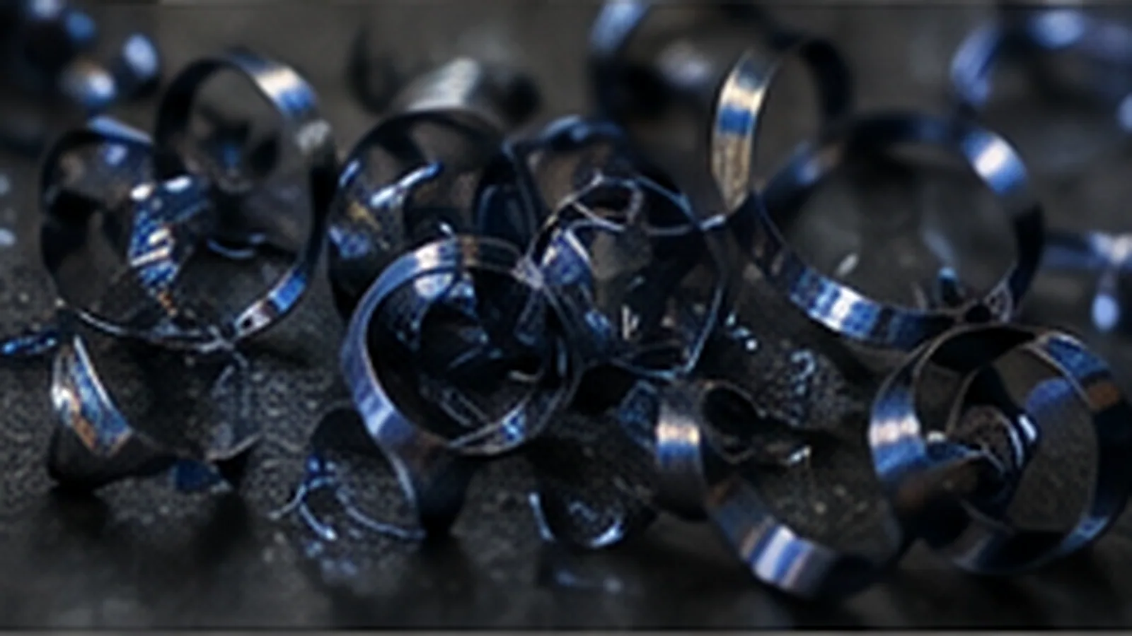 Copeaux d'inox longs et bleuis par la chaleur de coupe, teinte bleu acier caractéristique de la surchauffe.